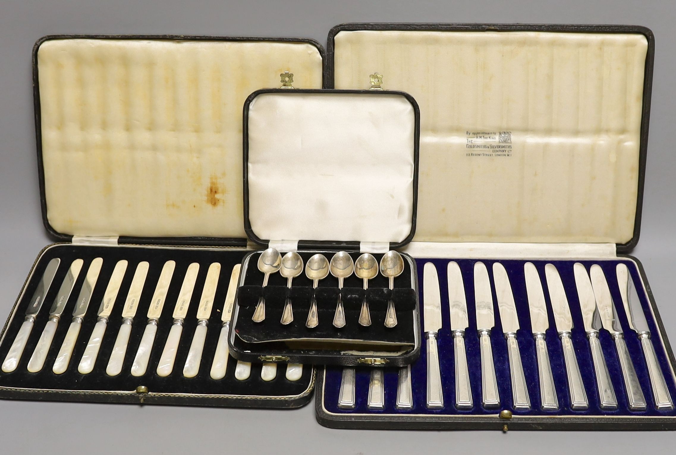 Two cased sets of silver or mother of pearl handled tea knives and a cased set of six silver teaspoons.